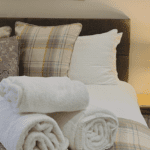 A cosy bed with a countryside feel, dressed in luxurious Egyptian cotton bedding and neatly folded towels, creating a serene and inviting atmosphere.