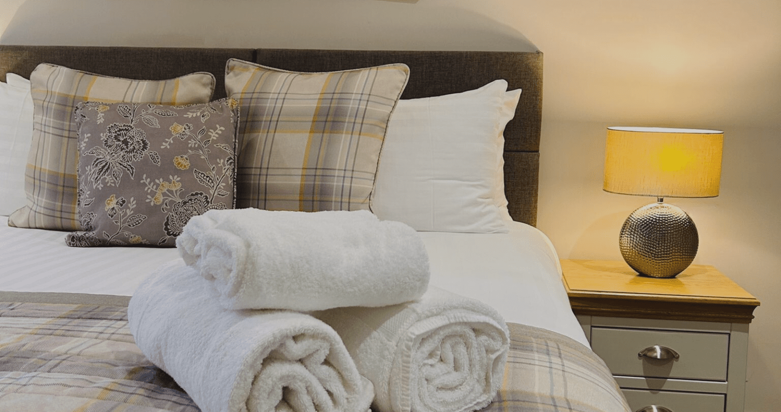 A cosy bed with a countryside feel, dressed in luxurious Egyptian cotton bedding and neatly folded towels, creating a serene and inviting atmosphere.