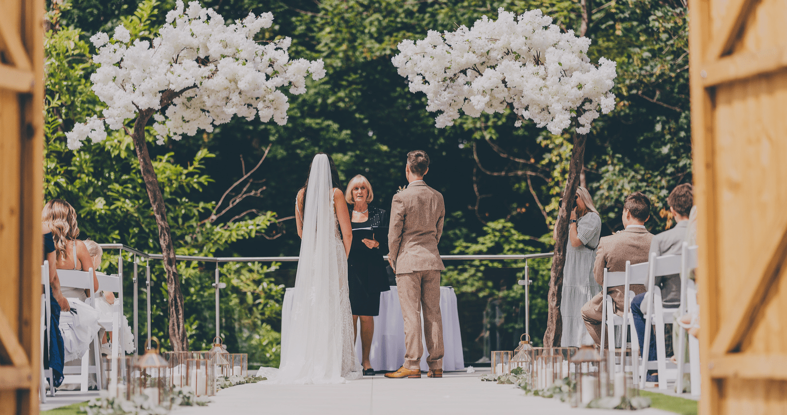 Picturesque outdoor countryside wedding ceremony in a secret garden, set against a woodland backdrop, with elegant seating and natural greenery.