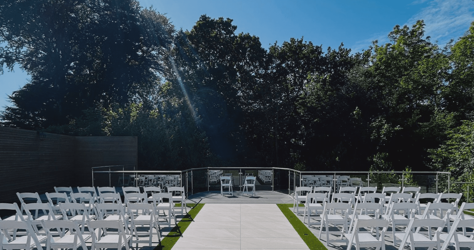 Serene wedding trend setting outdoors for drinks reception, chairs setup as theatre style facing the woodland background in the secret garden