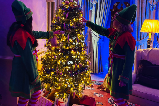 Two festive elves decorating a beautifully lit Christmas tree inside De Courceys Manor, adding holiday cheer to the venue.