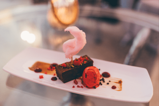 Exquisite dessert featuring rich chocolate and topped with pink candy floss, served on a beautifully plated dish for an elegant dining experience.