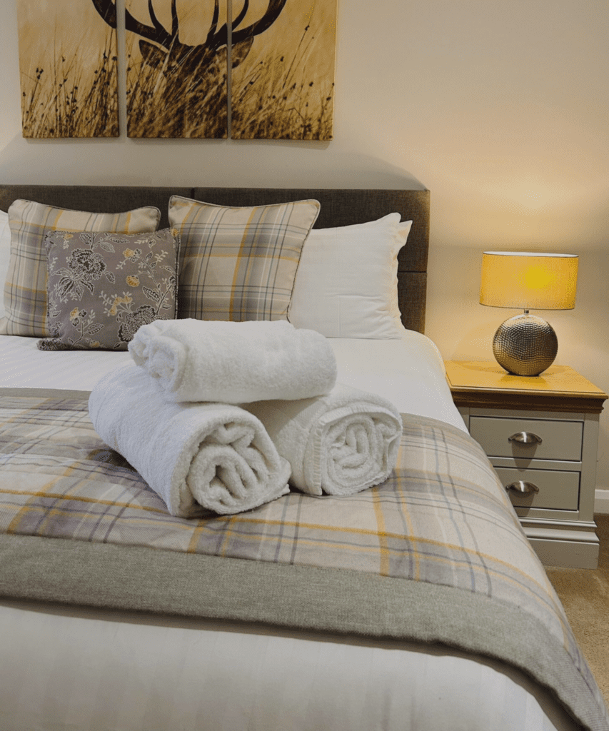 A cosy bed with a countryside feel, dressed in luxurious Egyptian cotton bedding and neatly folded towels, creating a serene and inviting atmosphere.