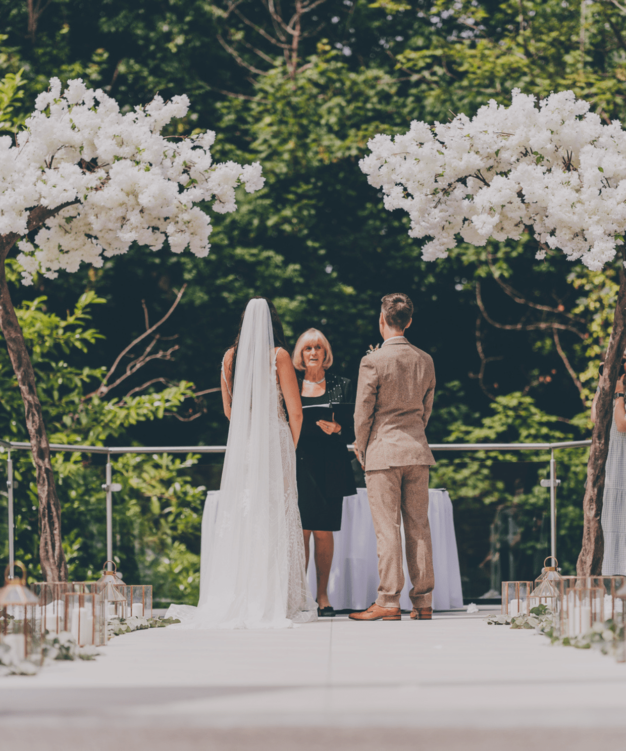 Picturesque outdoor countryside wedding ceremony in a secret garden, set against a woodland backdrop, with elegant seating and natural greenery.